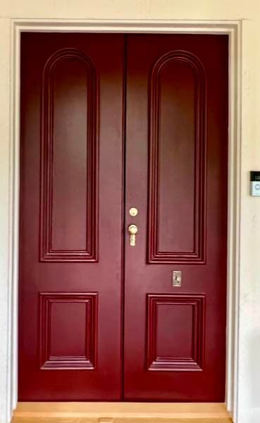 Custom arched-panel double entry doors with a transom, painted deep red