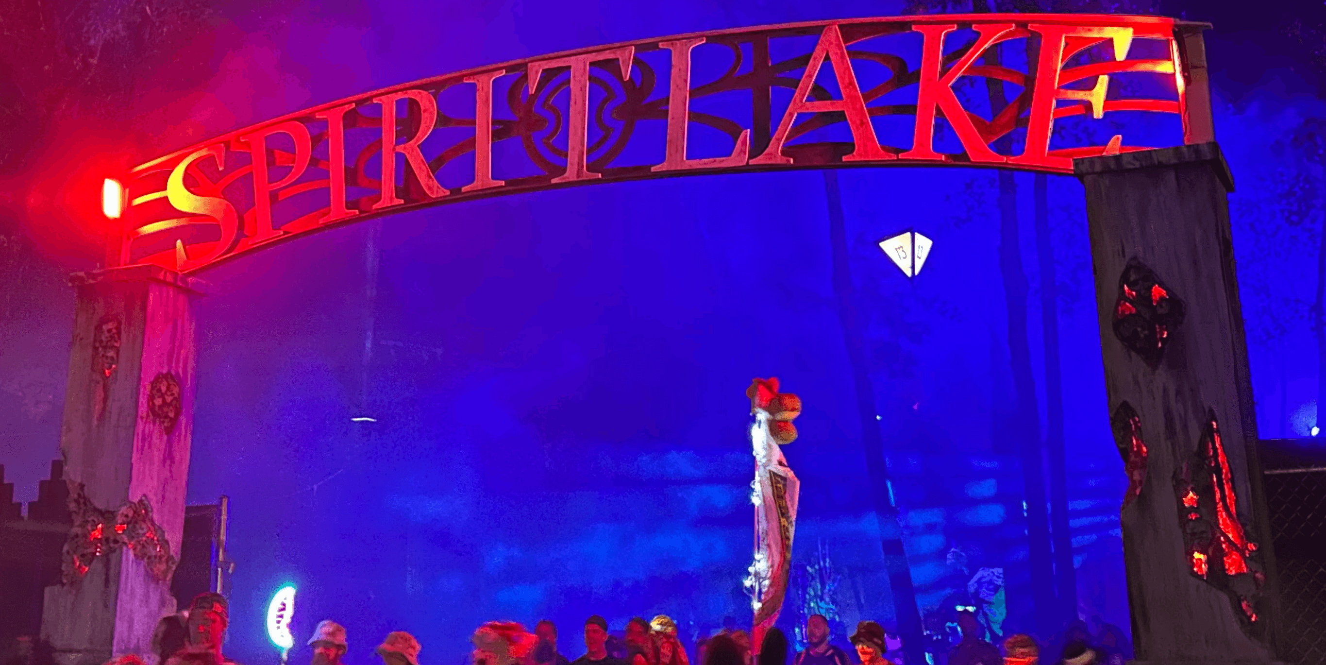 Large cut-panel Spirit Lake entry arch with ornate letterforms lit red between faux-stone pylons at night