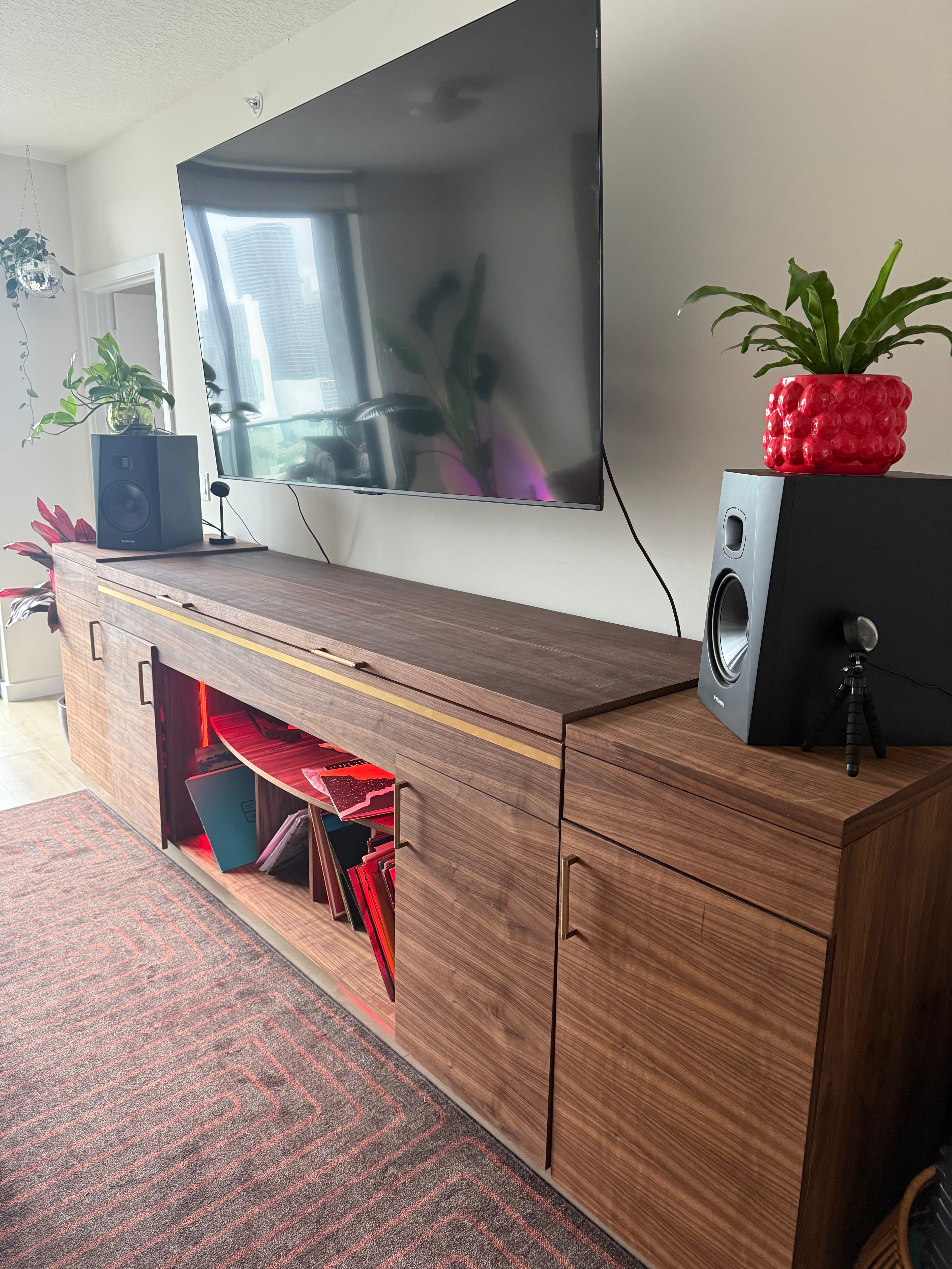 Walnut media console with brass inlay, seen three-quarter, integrated record storage