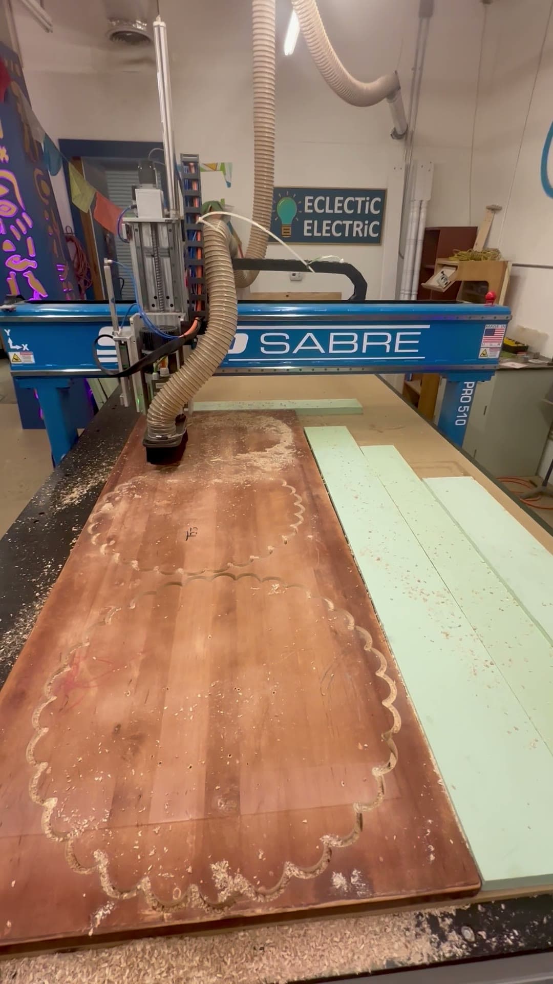 The router cutting a curved profile into a red solid-surface sheet
